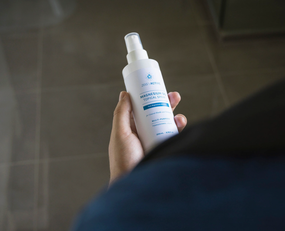 Hand holding a bottle of Zea magnesium oil spray
